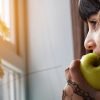 This shows a little girl eating an apple