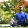 This shows a man meditating in a park